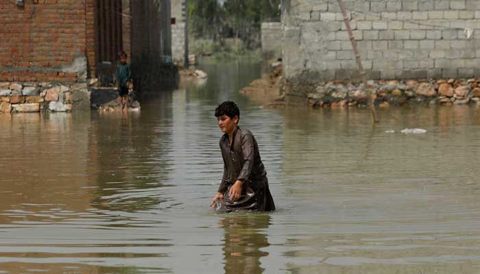 A boy makes his way through stranded flood water, following rains and floods during the monsoon season in Nowshera. — Reuters/File
