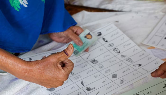 A voter with an ink mark on the thumb goes through paperwork to cast a vote during the general election in Karachi, on February 8, 2024. — Reuters